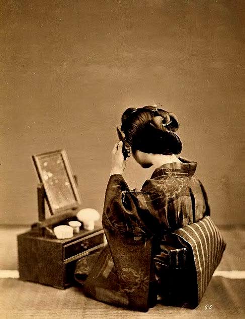 Geisha-using-her-mirror Vintage photo of a Geisha preparing hair