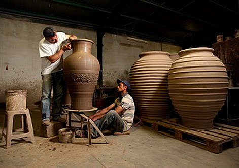 cretan-pottery-logo Two potters at Cretan pottery creating a large pot