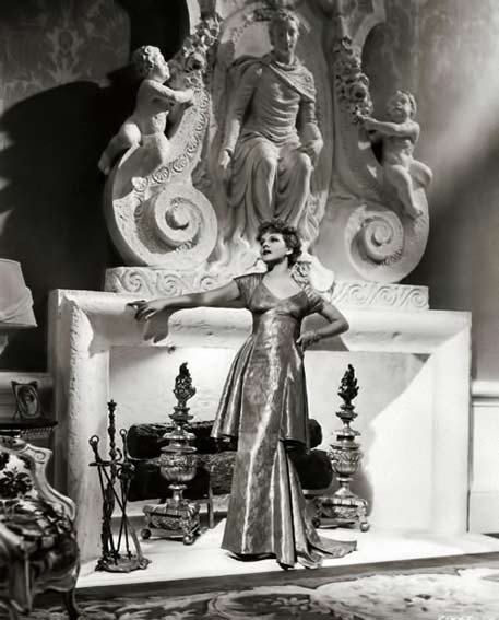 Elissa-Landi-posing-at-grand-fireplace Elissa-Landi at huge white fire place