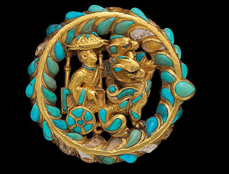 golden-boot-buckles-afghanistan golden-boot-buckle--decorated-with-turquoise-and-carnelian A man rides under a parasol in a cart pulled by a pair of winged felines.