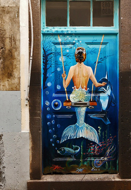 Mermaid-on-a-swing.-Madeira,-Portugal. Painted-door.-Mermaid-on-a-swing.-Madeira,-Portugal.