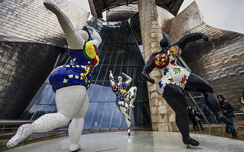 Niki-de-Saint-Phalle-nana-sculptures Sculptures-by-Niki-de-Saint-Phalle-at-the-entrance-to-the-Guggenheim,-Bilbao