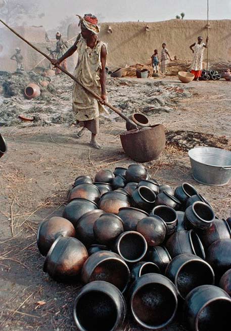 Women-firing-newly-made-pottery-in-the-village-of-Kalabougou-in-Mali,-Africa Large pottery firing pit in Mali